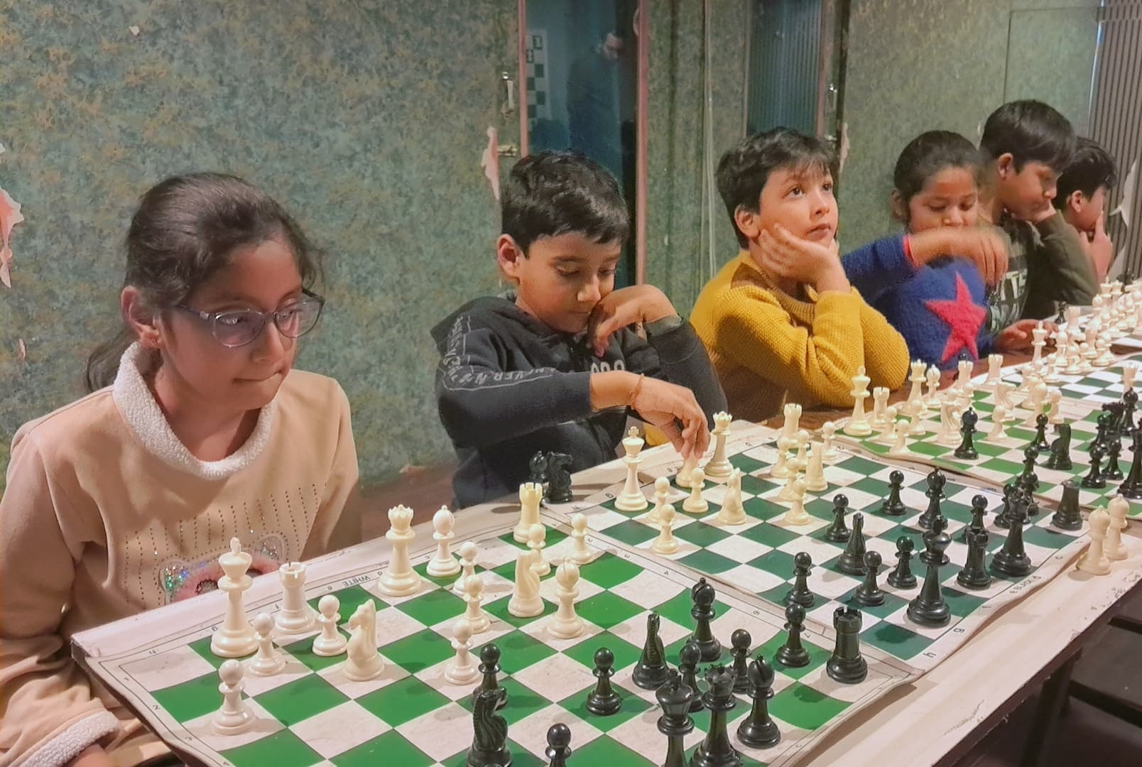 Children learning chess fundamentals in academy classroom